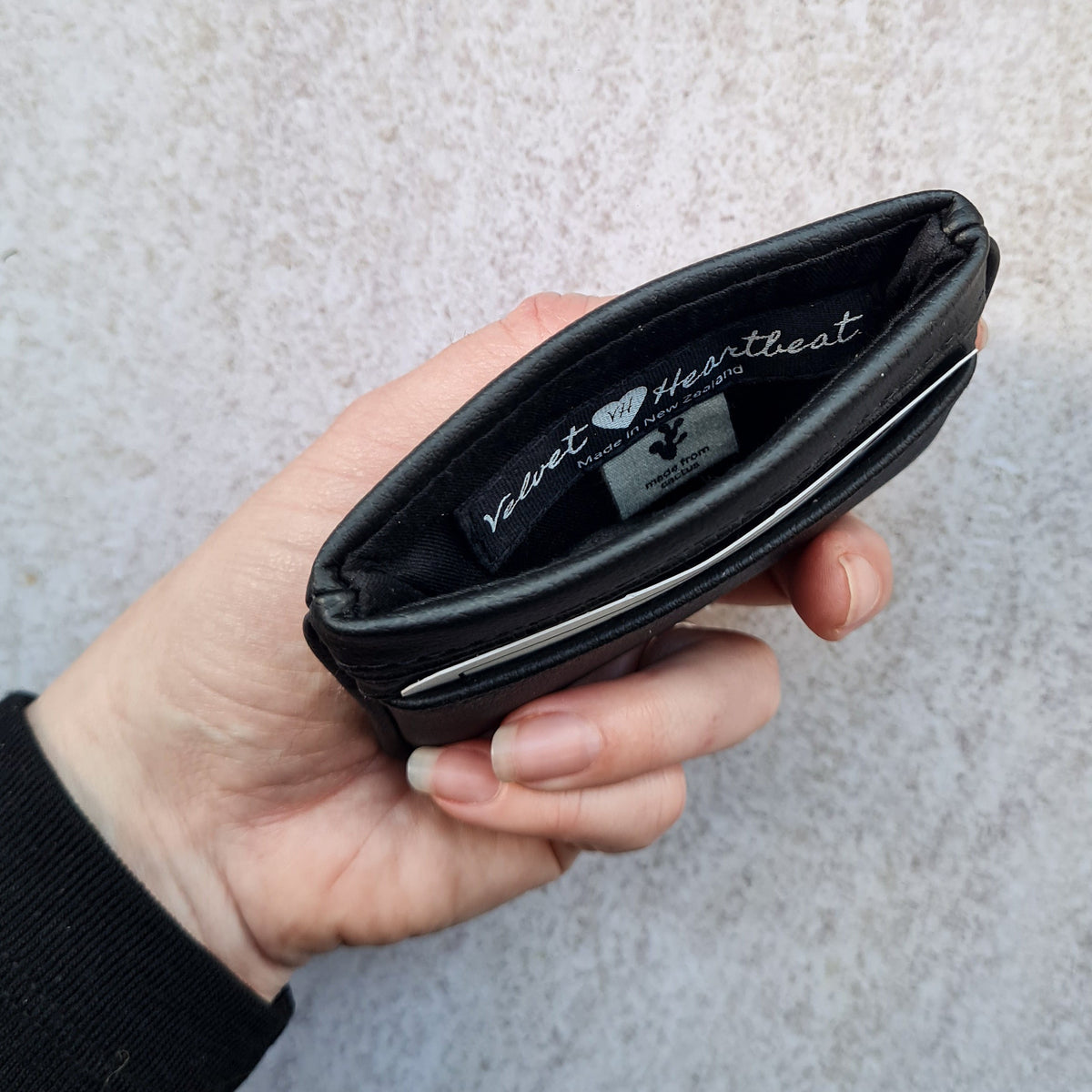 Black 5 card wallet made from vegan cactus leather with subtle piping detail on edge, showing middle pocket