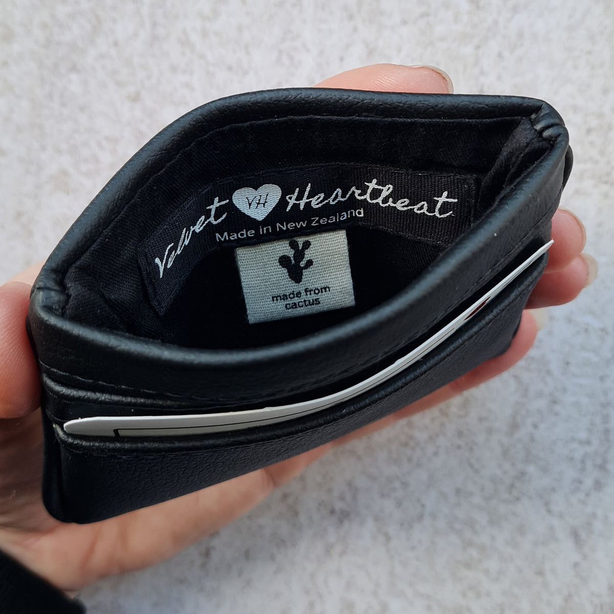 Black 5 card wallet made from vegan cactus leather with subtle piping detail on edge, showing middle pocket