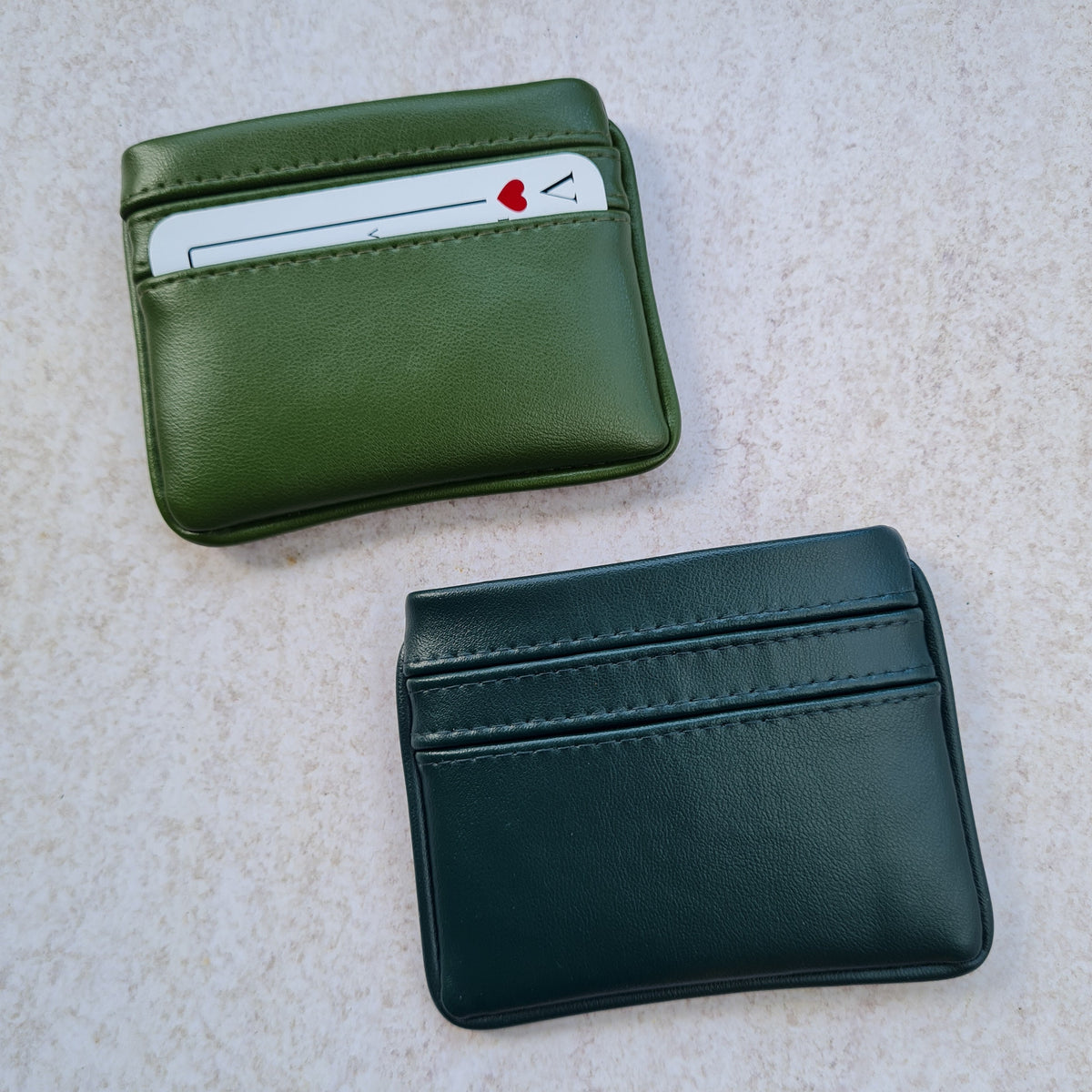 Two card wallets in nopal green and dark forest green with 5 card pockets made from vegan cactus leather with subtle piping detail on edge