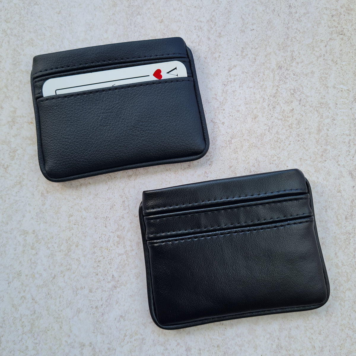 Two black card wallets in smooth and pebble texture, with 5 card pockets made from vegan cactus leather with subtle piping detail on edge
