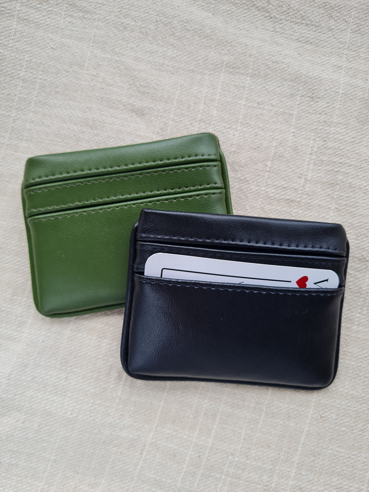 Two card wallets in nopal green and raven black with 5 card pockets made from vegan cactus leather with subtle piping detail on edge