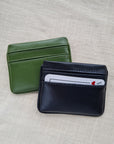 Two card wallets in nopal green and raven black with 5 card pockets made from vegan cactus leather with subtle piping detail on edge